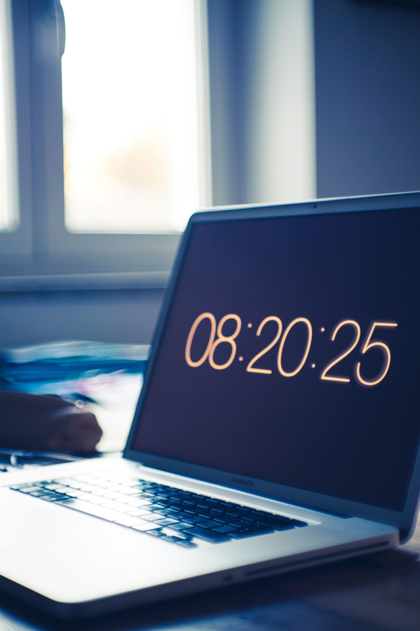 Laptop displaying digital clock on desk in an office setting, evoking a tech-focused workspace.